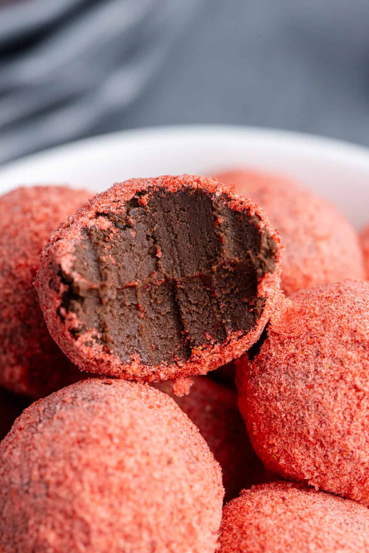 Strawberry Chocolate Truffles in a bowl stacked with a bite taken from one