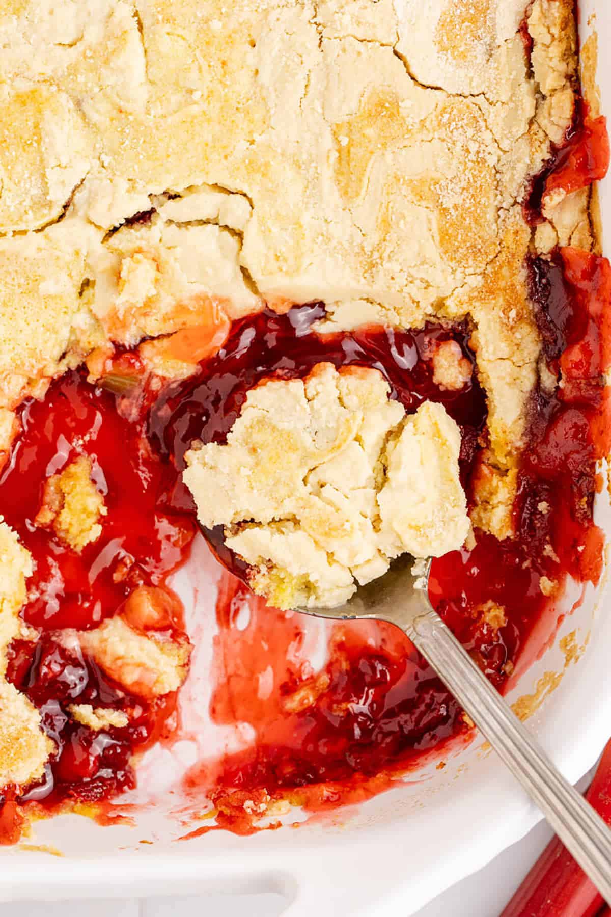 Strawberry Rhubarb Dump Cake in a casserole dish from above with a spoonful