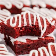 Red Velvet Brownies with Frosting Drizzle Stacked with One Bite Taken to Show Texture