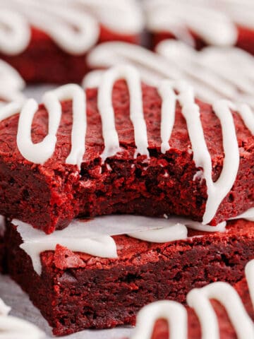 Red Velvet Brownies with Frosting Drizzle Stacked with One Bite Taken to Show Texture