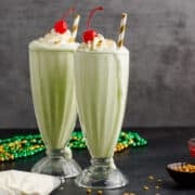 Shamrock Shakes on a countertop with cherries and whipped cream