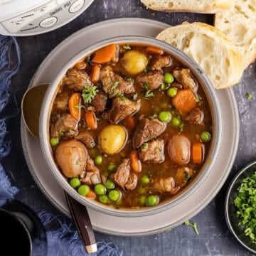 Crock Pot Lamb Stew in a bowl from above with a slow cooker and bread beside