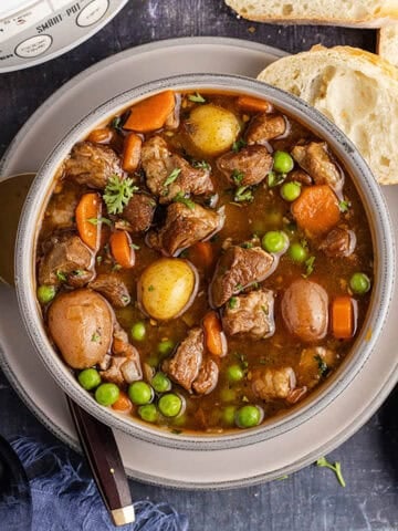 Crock Pot Lamb Stew in a bowl from above with a slow cooker and bread beside