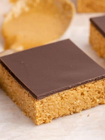 No Bake Peanut Butter Bars on parchment with a spoon behind