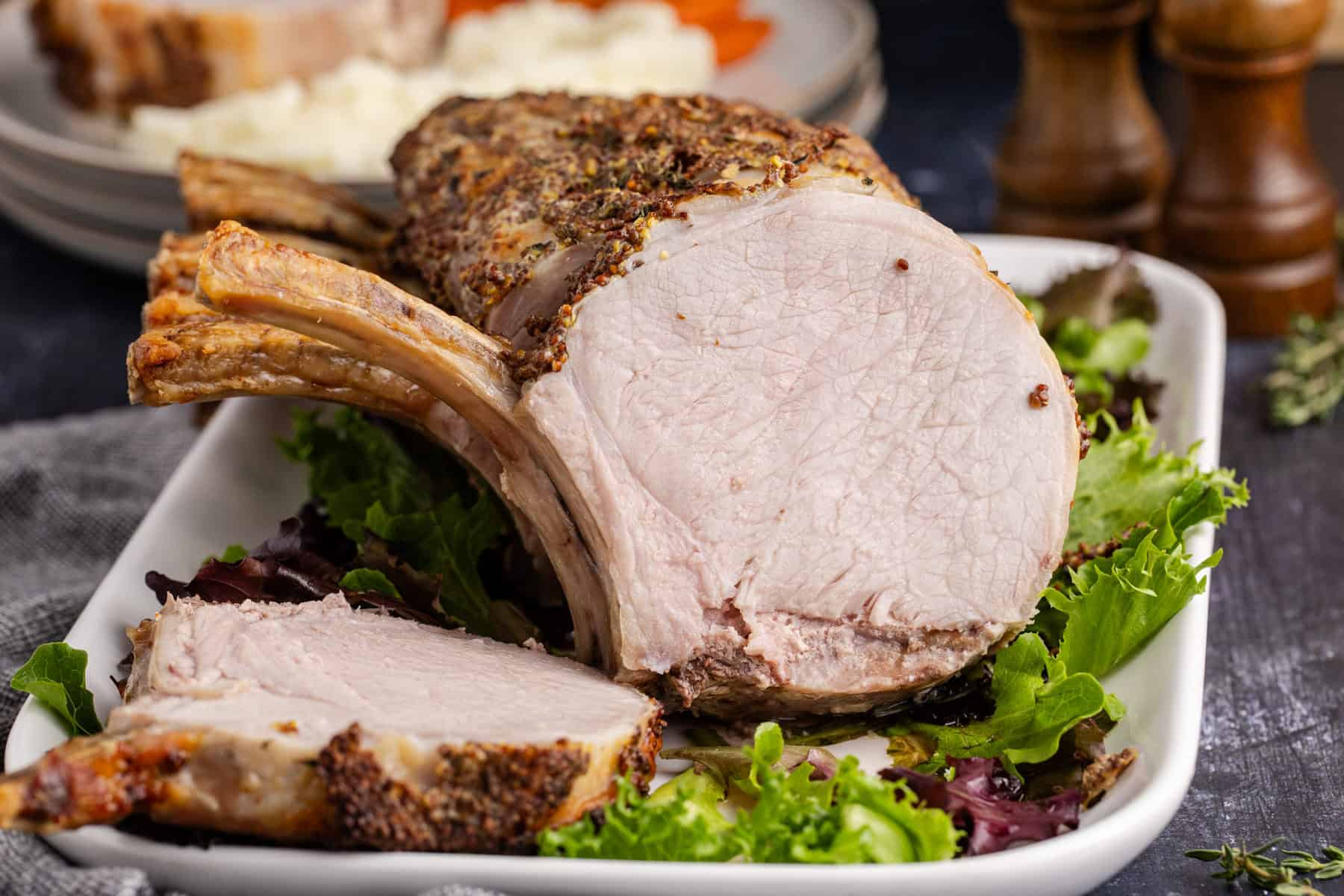 Pork Prime Rib cooked on a platter with a slice facing forward