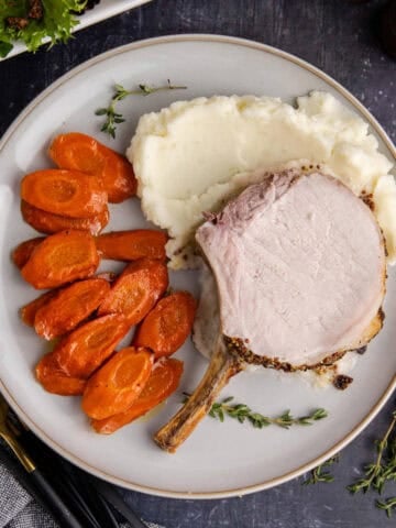 Pork Prime Rib on a plate with carrots and mashed potatoes