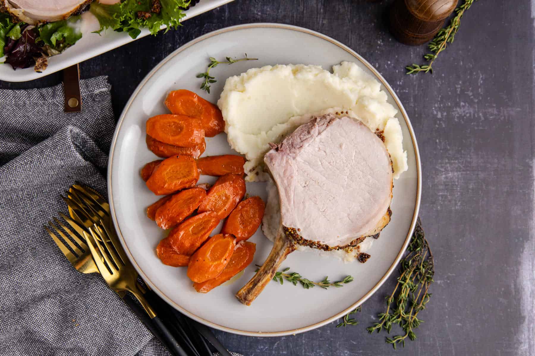 Pork Prime Rib on a plate with carrots and mashed potatoes