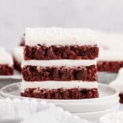 Red Velvet Cookies Bars stacked on a plate with icing and sprinkles