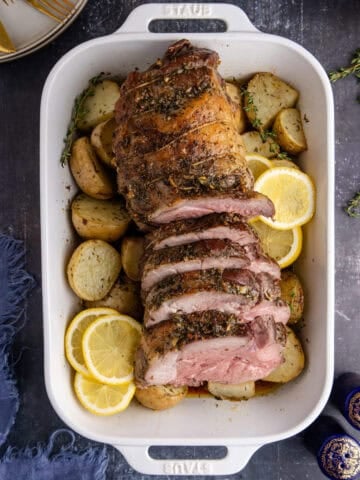 Roast Leg of Lamb slices in the casserole dish on a bed of potatoes from above