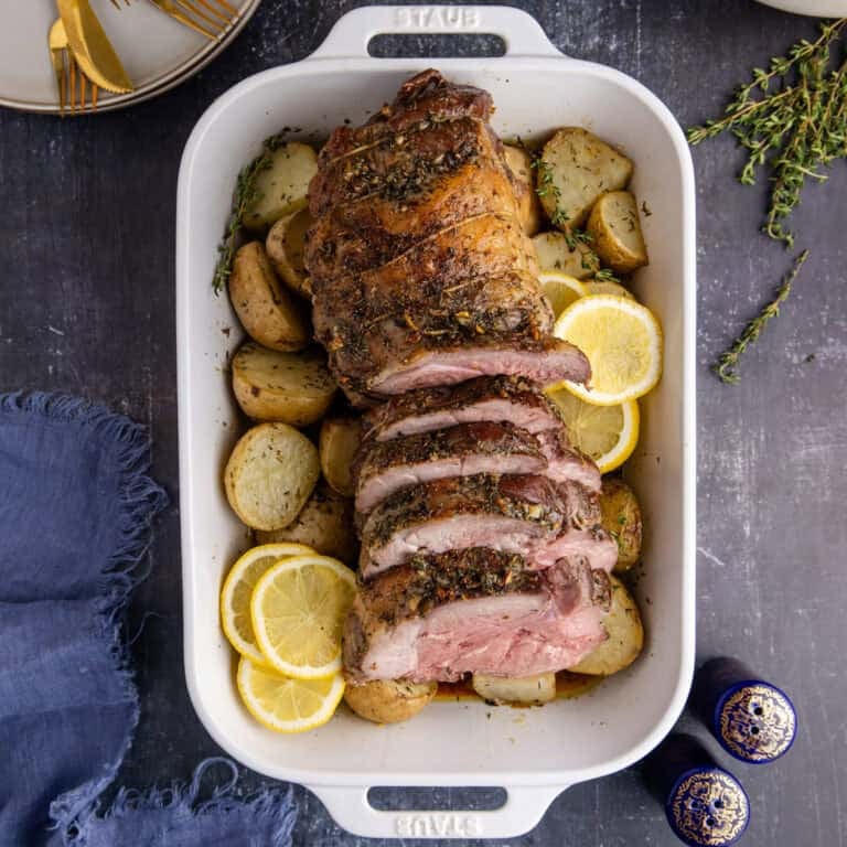 Roast Leg of Lamb slices in the casserole dish on a bed of potatoes from above