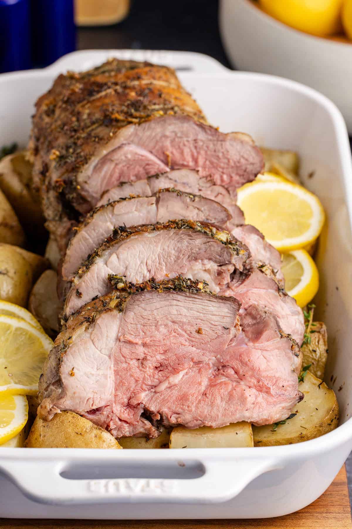 Roast Leg of Lamb slices in the casserole dish on a bed of potatoes