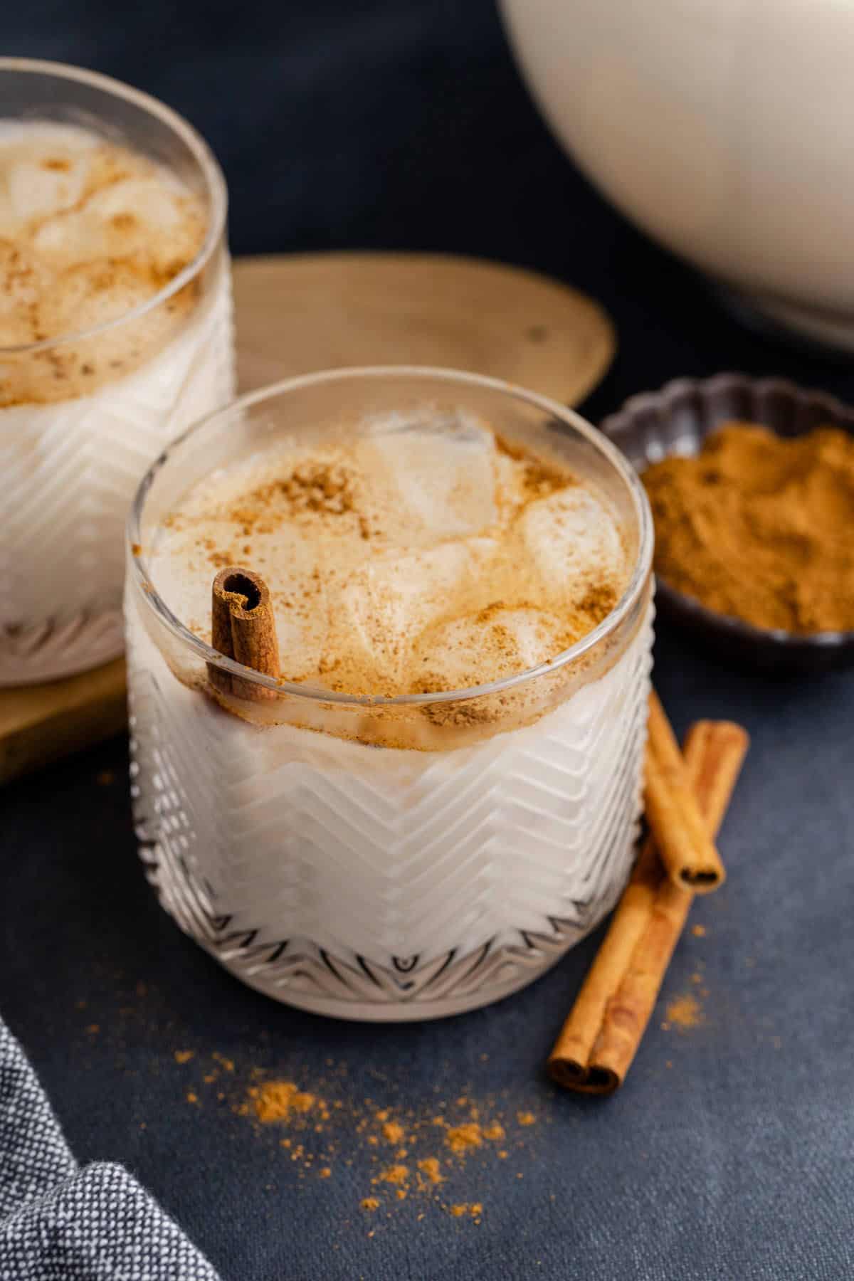 Agua de Horchata with cinnamon sticks beside and ground cinnamon in the back