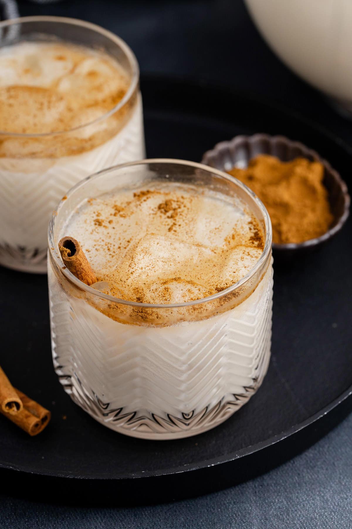 Agua de Horchata in a glass on a serving tray with cinnamon sticks