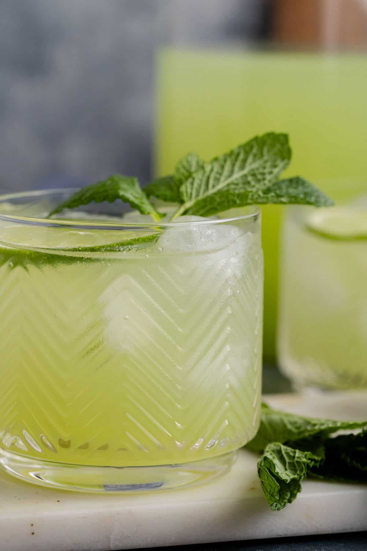 Cucumber Agua Fresca on a cutting board with limes and mint up close
