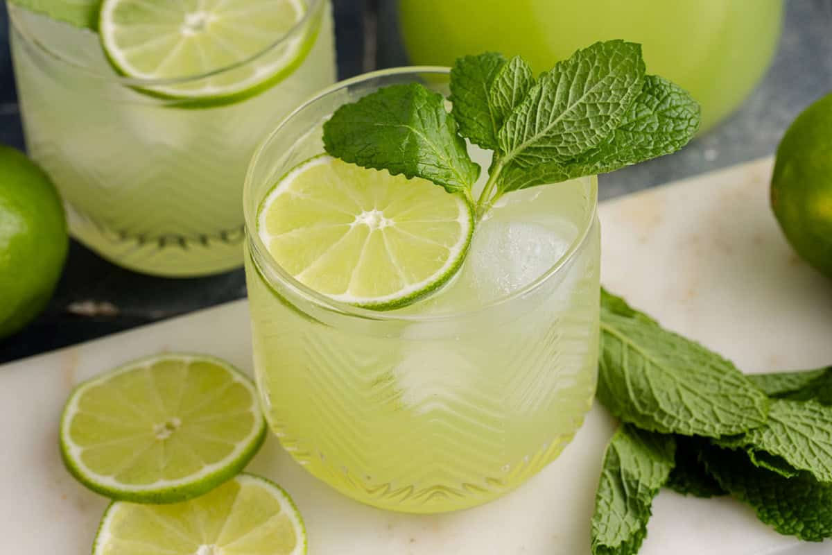 Cucumber Agua Fresca on a cutting board with limes and mint