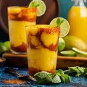Mangonada with mango chunks around it a lime and mint garnish