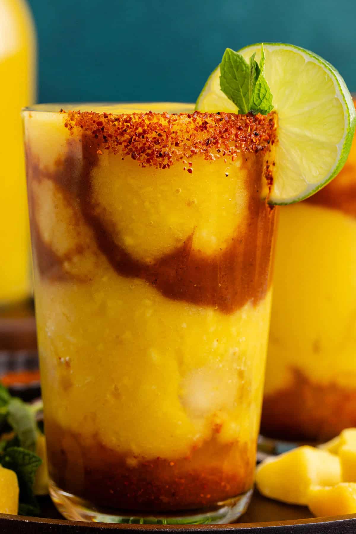 Mangonada with mango chunks around it a lime and mint garnish