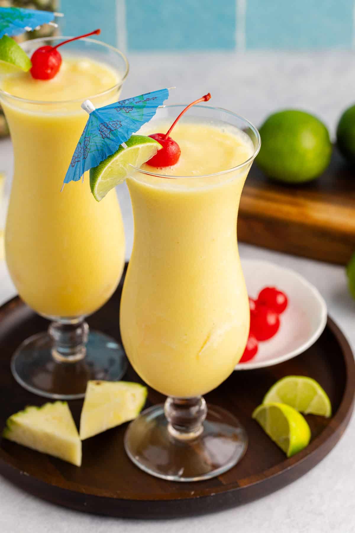 Two Non Alcoholic Frozen Pineapple Daiquiris with a cherry, lime and umbrella garnish