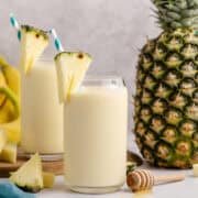 Pineapple Banana Smoothie with Coconut Milk on a counter and a pineapple in the back
