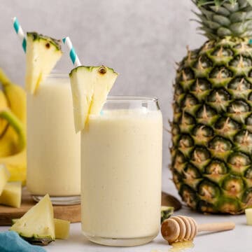 Pineapple Banana Smoothie with Coconut Milk on a counter and a pineapple in the back