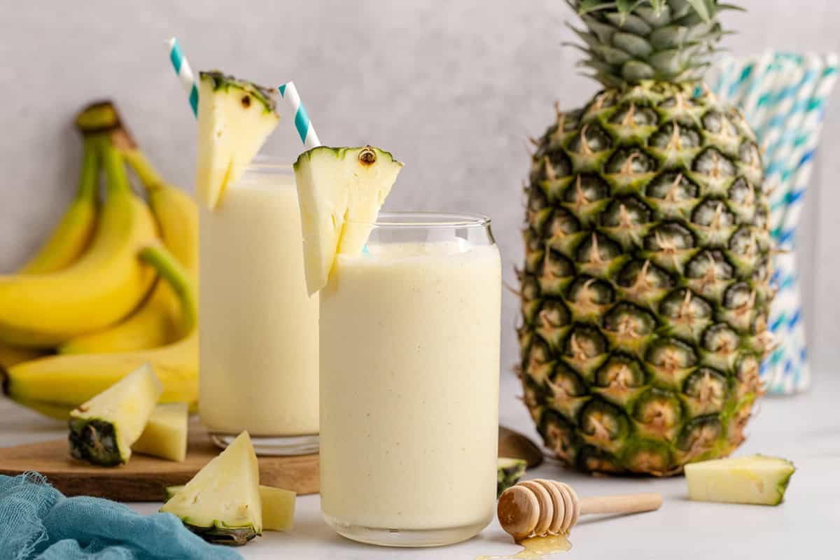 Pineapple Banana Smoothie with Coconut Milk on a counter and a pineapple in the back