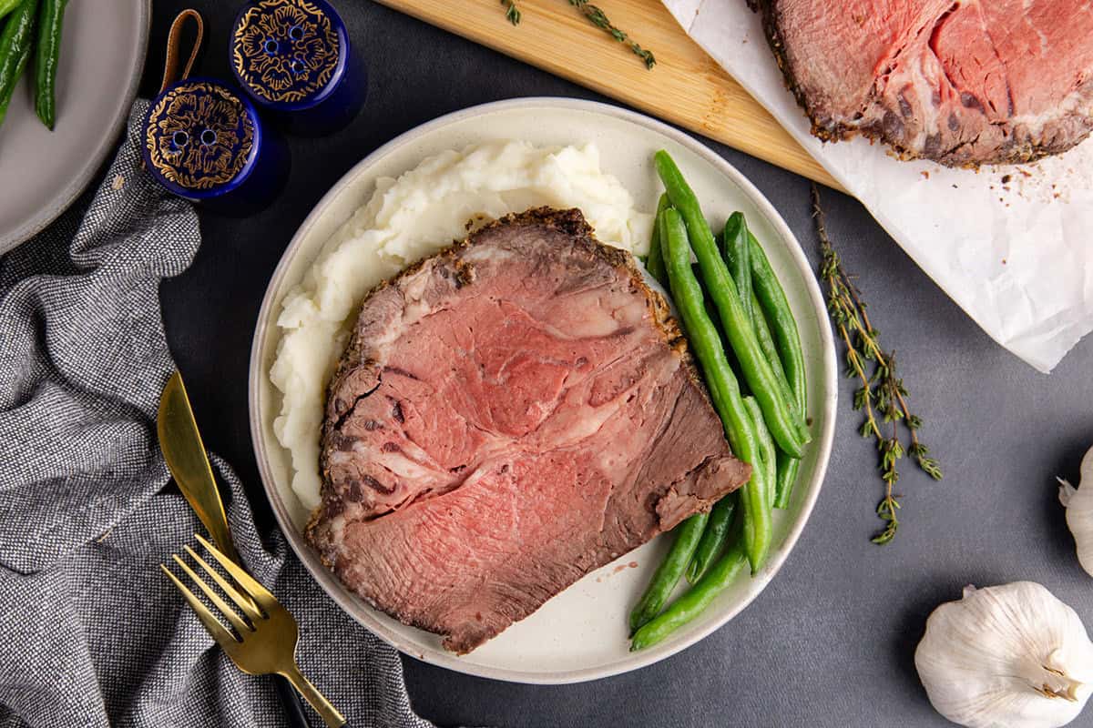 Poor Man's Prime Rib on a plate with mashed potatoes and beans