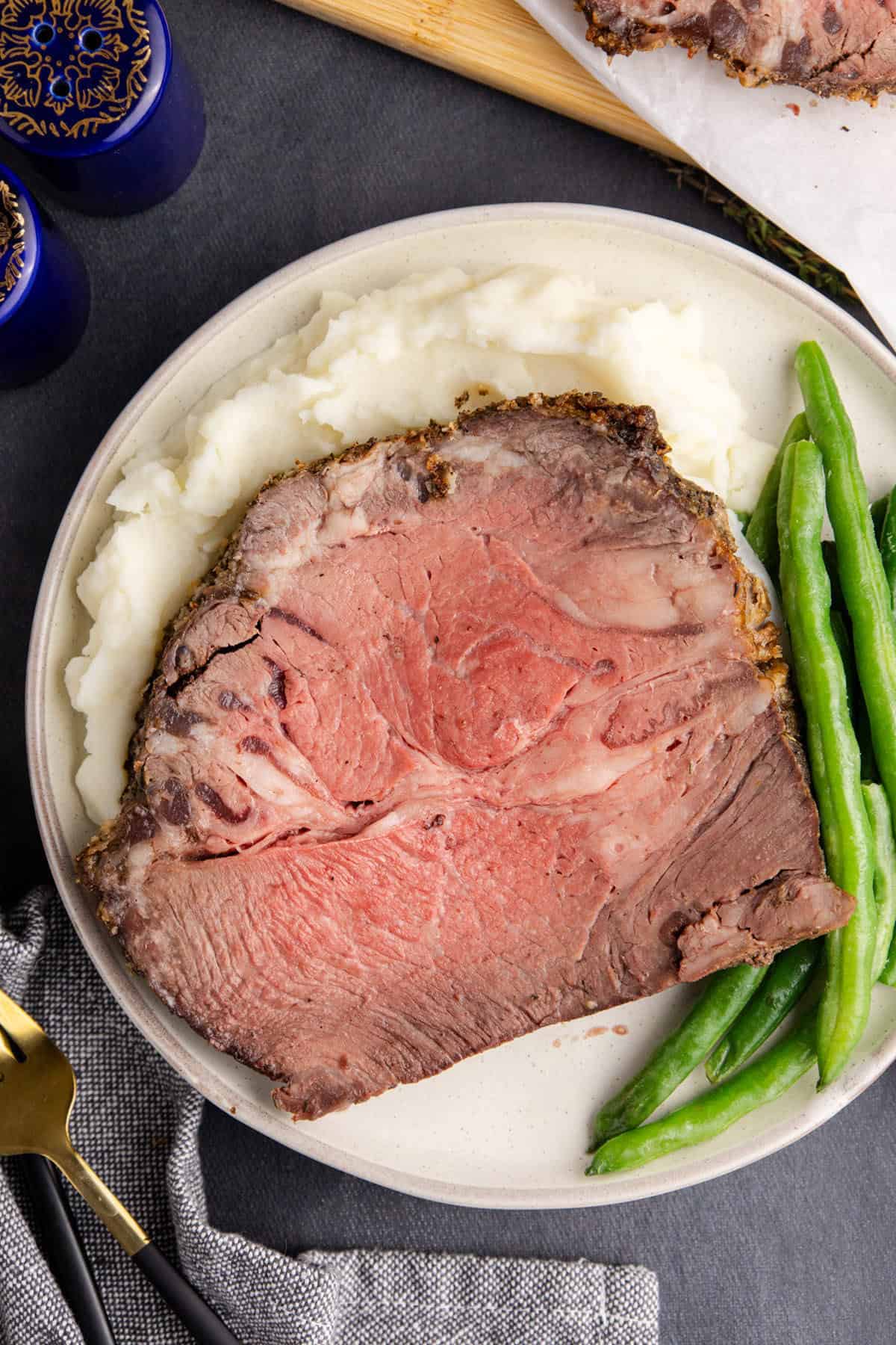 Poor Man's Prime Rib on a plate with mashed potatoes and beans