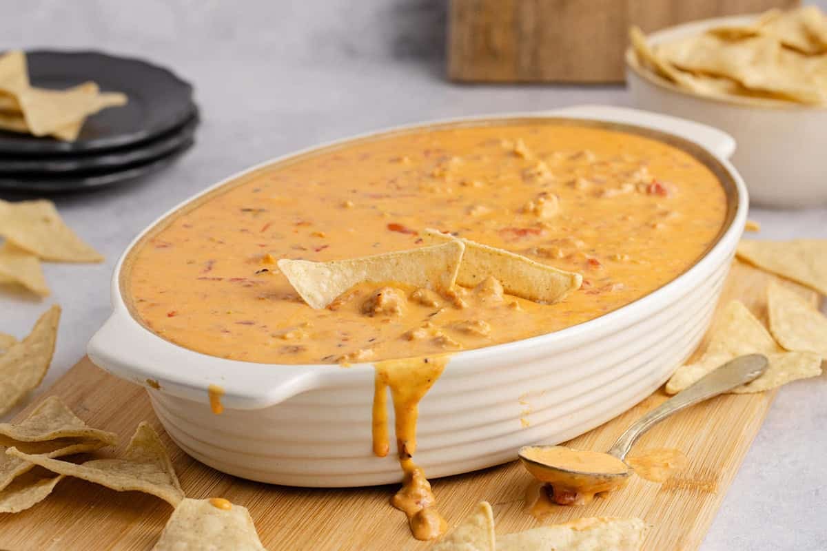 Spicy Sausage Queso in an oval dish with cheese dripping down the front
