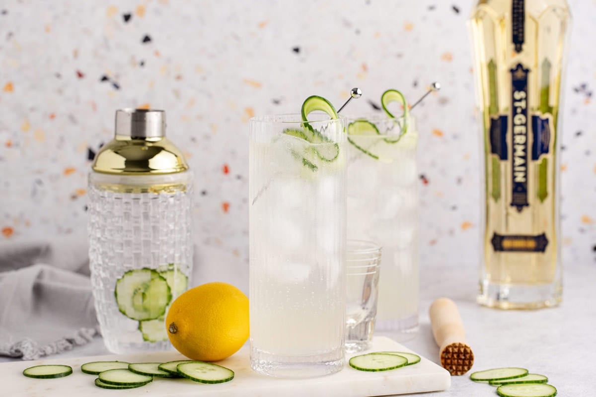 Cucumber Agua Fresca on a cutting board with a bottle of St-Germain in the back