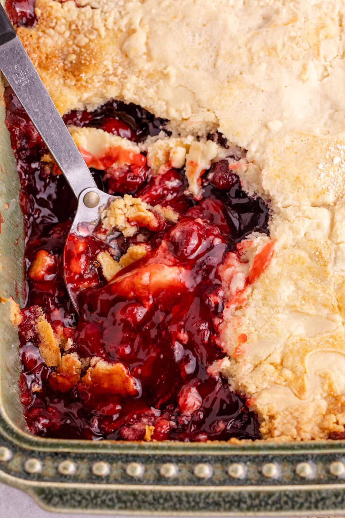 Strawberry Dump Cake in a baking dish with a serving spoon