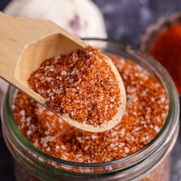 Brisket Rub in a small mason jar and a small wooden spoon hovering above