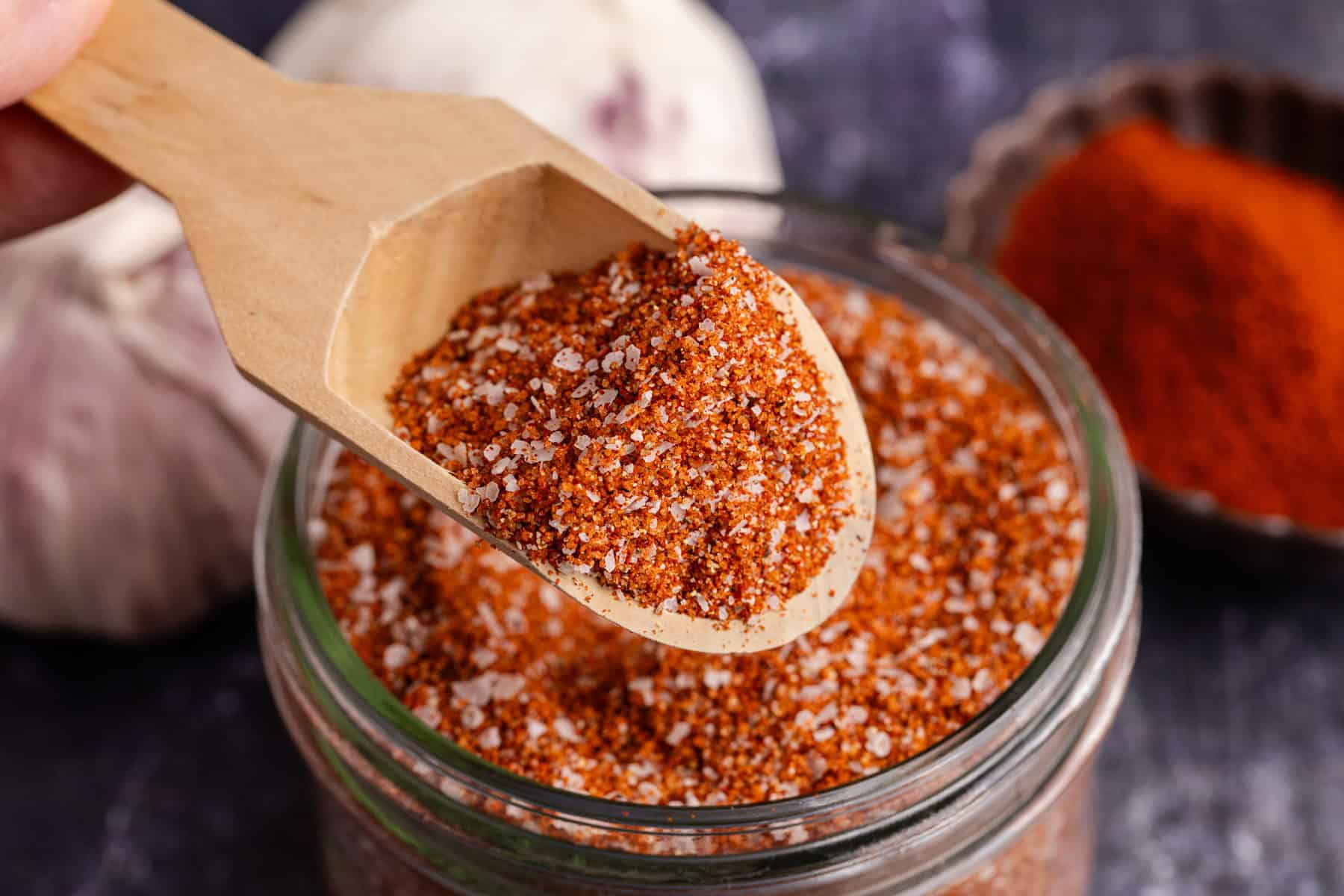Brisket Rub in a small mason jar and a small wooden spoon hovering above