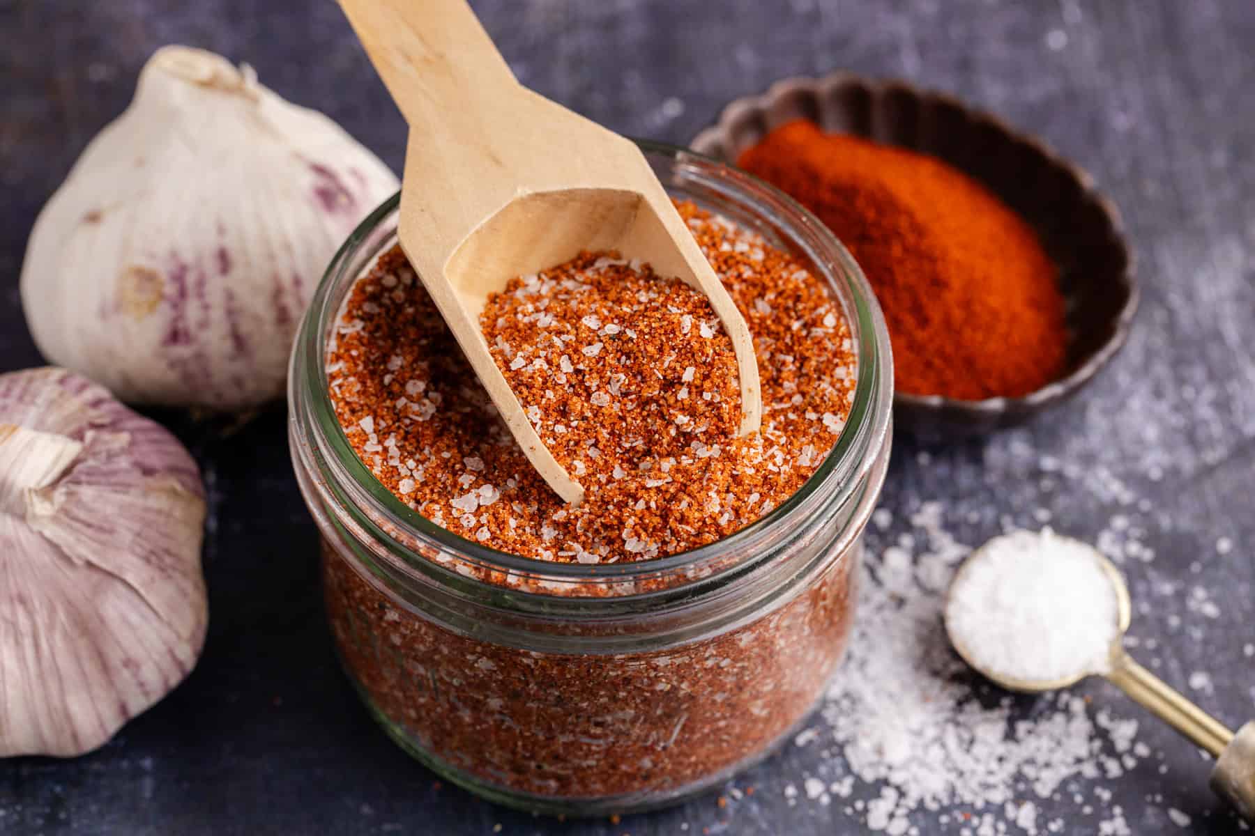 Brisket Rub in a small mason jar and a small wooden spoon on top