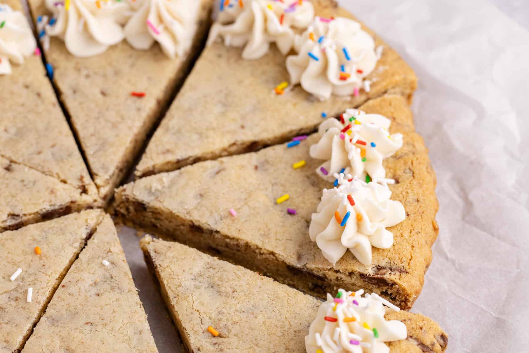 Chocolate chip cookie cake with white icing and rainbow sprinkles