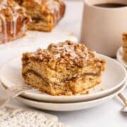 Cinnamon coffee cake slice on a stack of plates with a piece taken