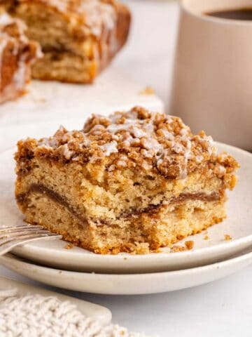 Cinnamon coffee cake slice on a stack of plates with a piece taken