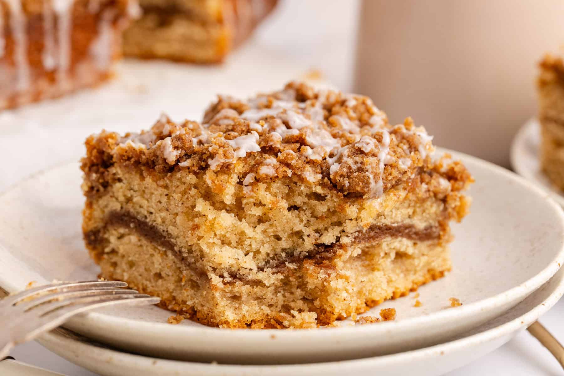Cinnamon coffee cake slice on a stack of plates with a piece taken