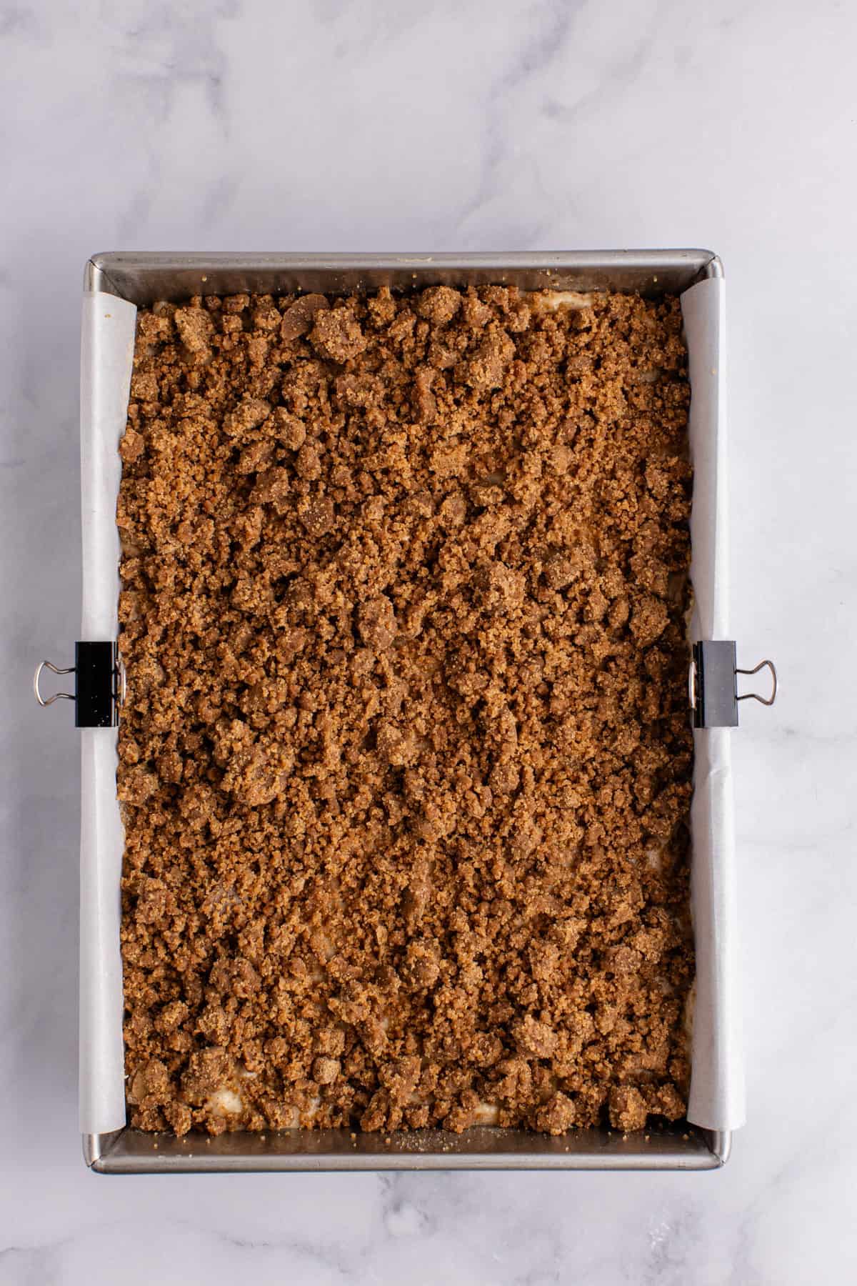 Cinnamon coffee cake in a 9x13 metal baking pan with the crumble on top
