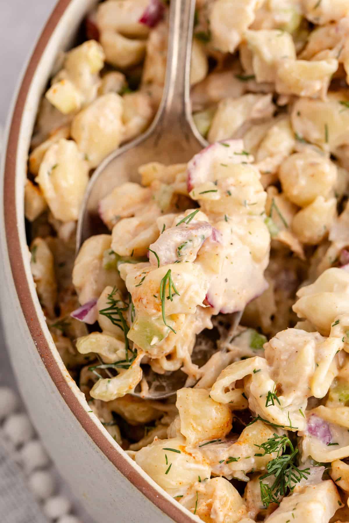 Cold Tuna Pasta Salad in a serving bowl close up with a spoonful