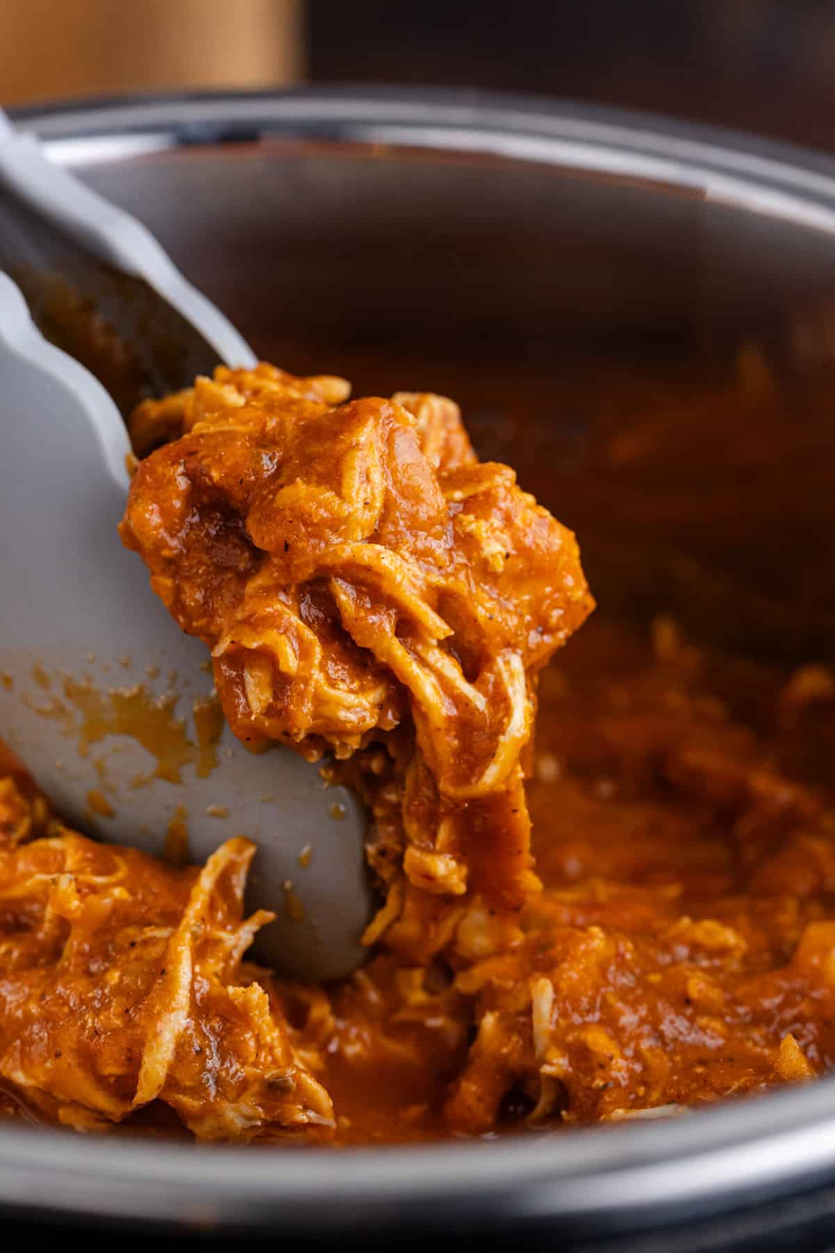 Instant Pot Chicken Tinga being picked up on tongs close up