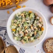 Keto broccoli salad in a bowl on a counter with cheese in the background