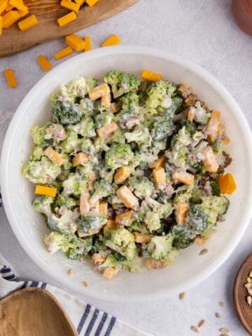 Keto broccoli salad in a bowl on a counter with cheese in the background