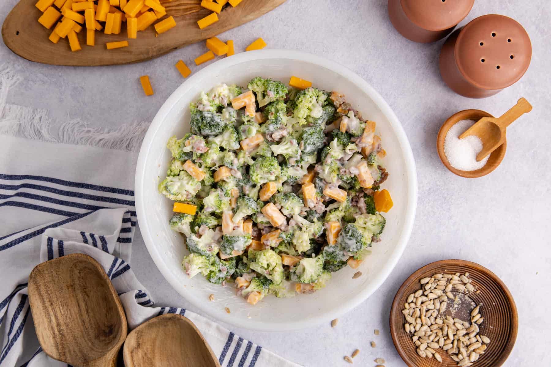 Keto broccoli salad in a bowl on a counter with cheese in the background