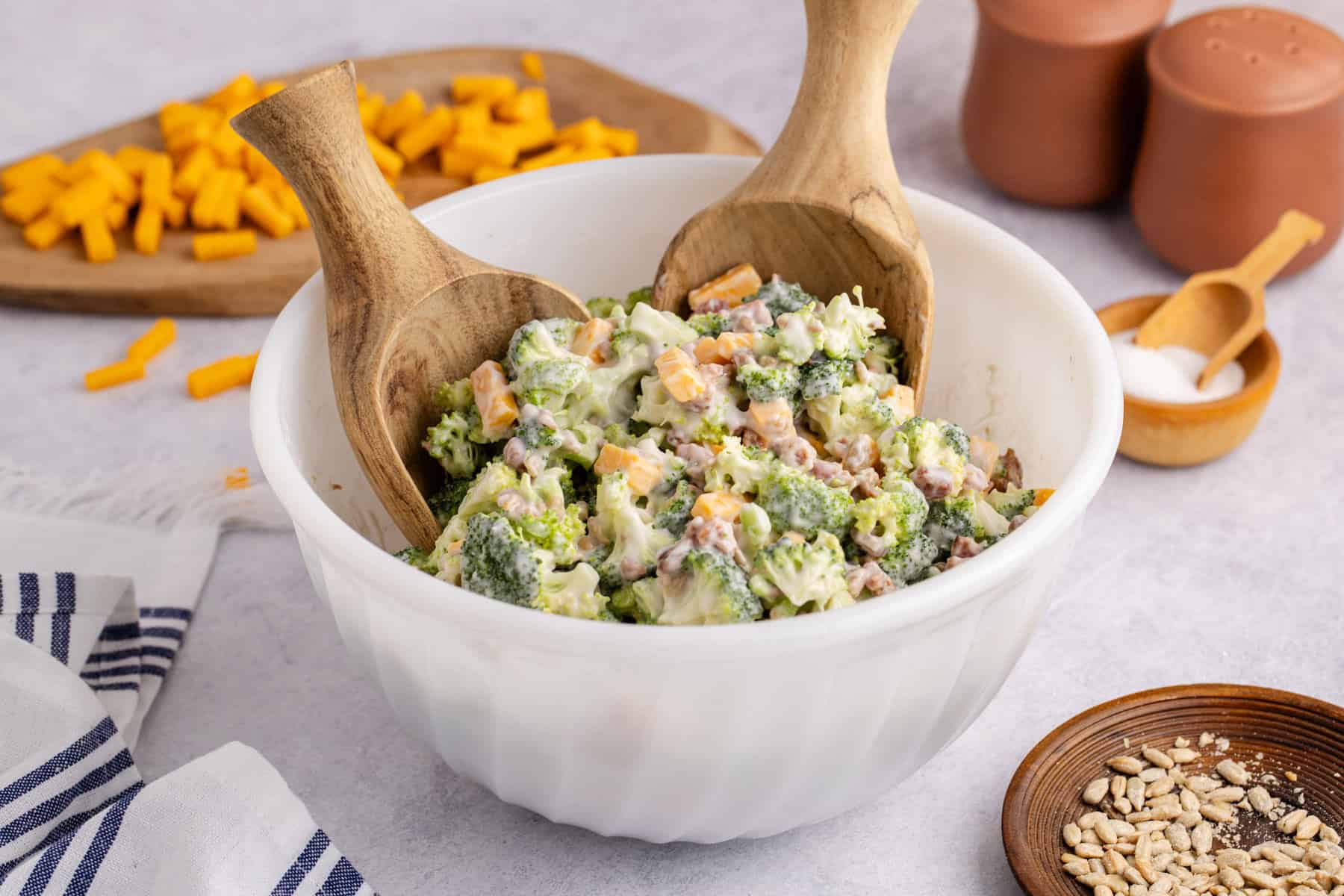 Keto broccoli salad in a bowl on a counter with cheese in the background