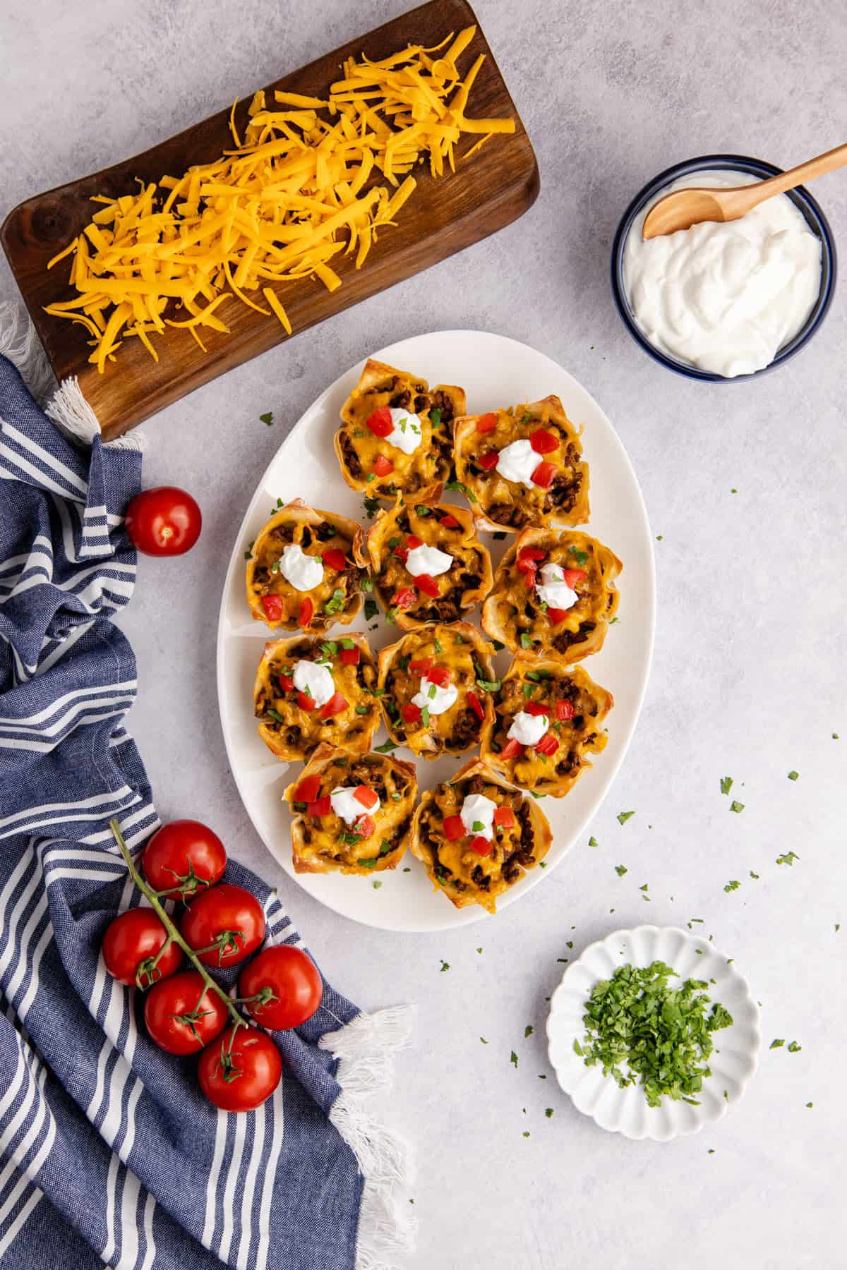 Mini Taco Cups on a platter with sour cream, tomatoes and cilantro from above