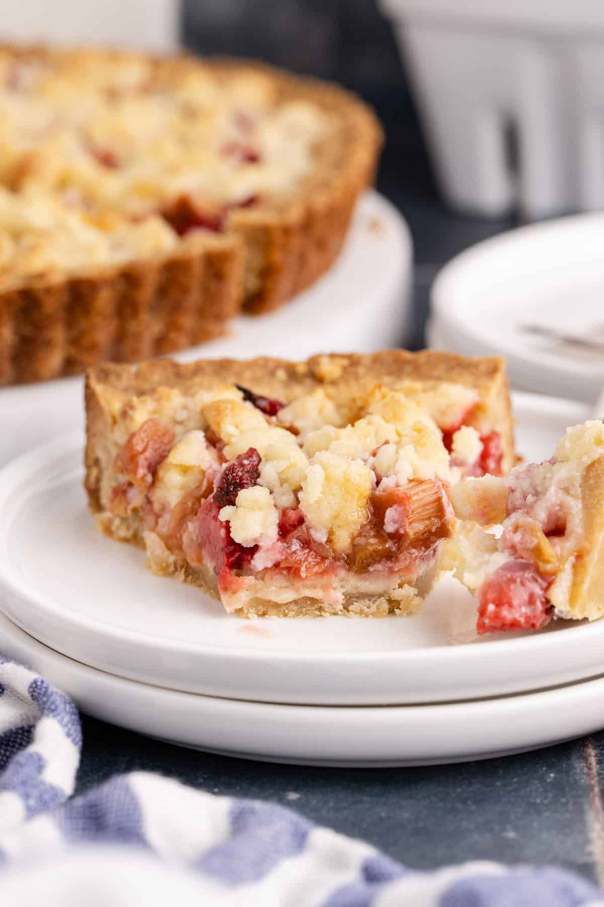 Strawberry Rhubarb Tart on a plate with a piece taken