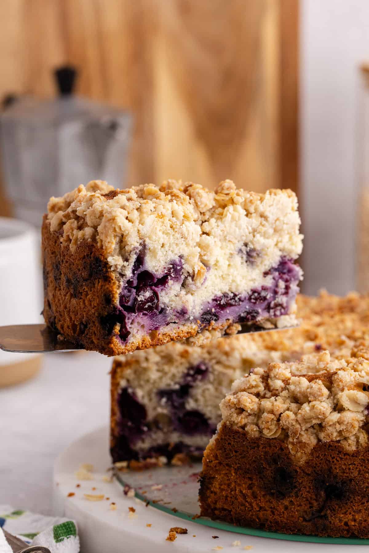 Blueberry Coffee Cake on a pie server being taken from the whole cake