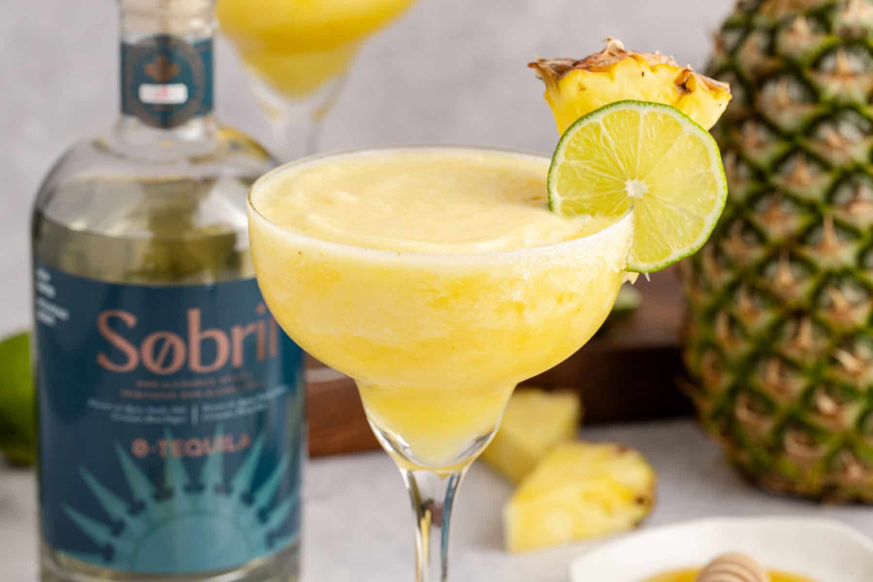 Frozen Non Alcoholic Pineapple Margarita with a bottle of zero proof tequila