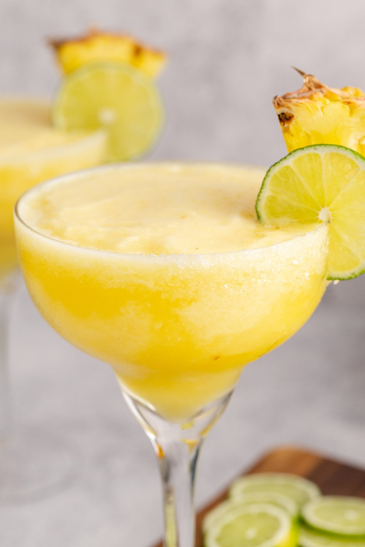 Frozen Non Alcoholic Pineapple Margarita close up with a lime round and pineapple on the rim