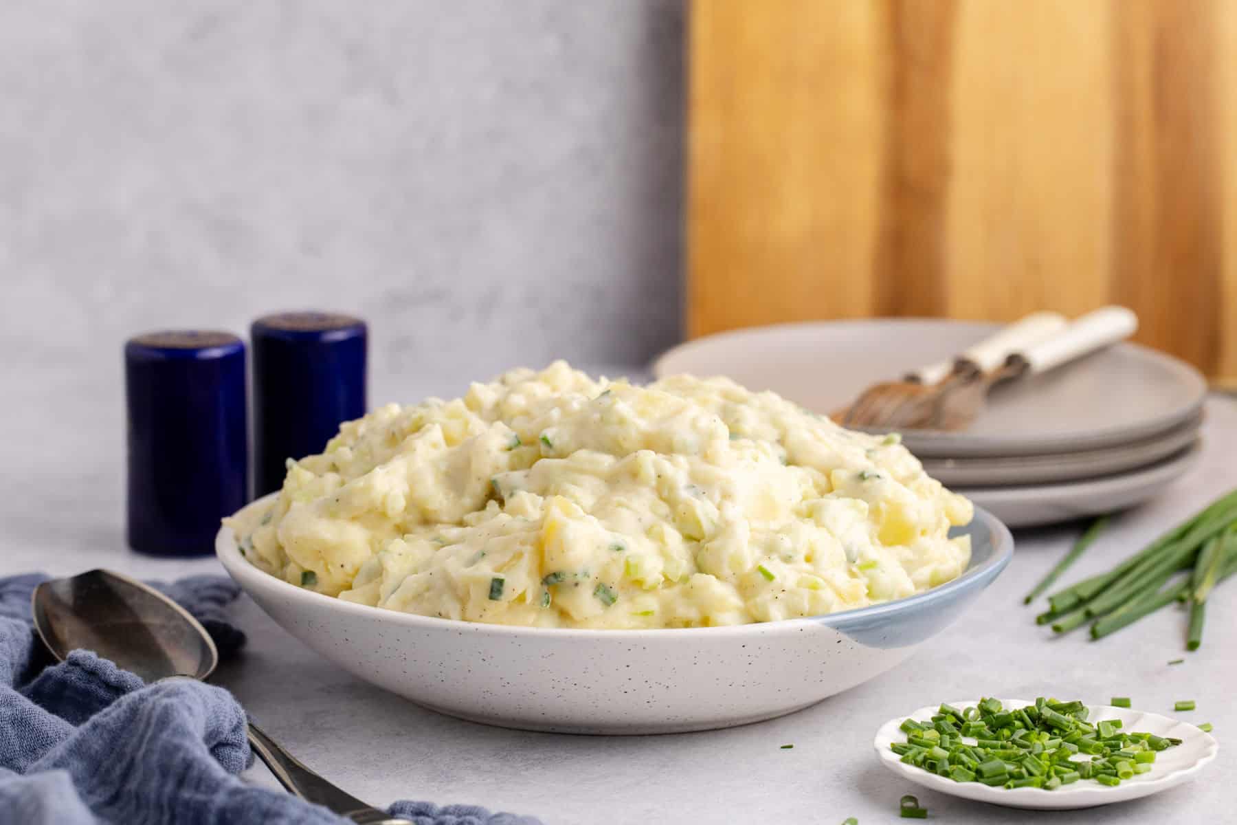 Potato Salad without Eggs in a serving bowl with plates in the back